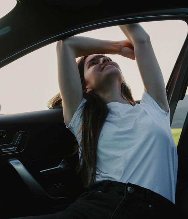 Woman smiling and stretching in a bright, sunlit room, feeling energetic.